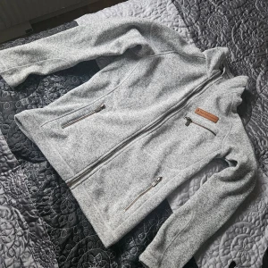 Grå fleecejacka från Peak Performance - Säljer en snygg och bekväm grå fleecejacka från Peak Performance. Jackan har en dragkedja framtill och två praktiska fickor med dragkedjor. Perfekt för kyliga dagar och passar både till vardags och utomhusaktiviteter. Den är i bra skick och redo för nya äventyr!