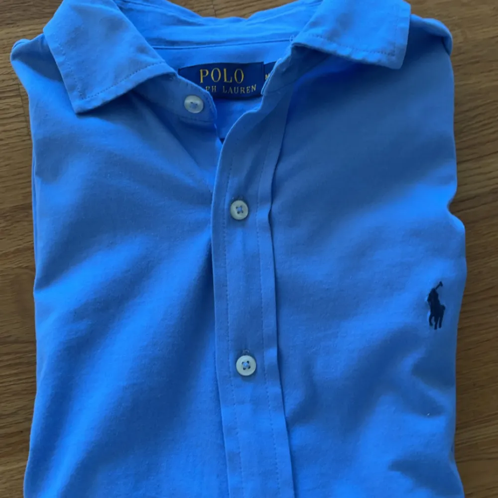 Säljer en snygg blå skjorta från Polo Ralph Lauren i storlek M. Skjortan är långärmad och har knappar hela vägen ner. Den är gjord av bomull och har en broderad logga på bröstet. Perfekt för både vardag och fest! Köpt för 1900 o jag säljer för 999. Skjortor.