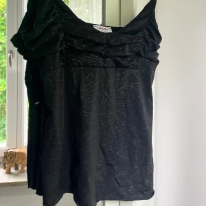 Glittrigt Linne - Glittrigt svart linne, storlek S, linnet är asymmetrisk längst ner men det märks knappt av! 
