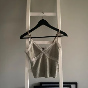 Grön ribbad linnetopp med spetsdetaljer - Säljer en superfin grön ribbad linnetopp med spetsdetaljer. Toppen är ärmlös och har smala axelband. Perfekt för sommaren eller en festkväll! Den är i bra skick och väldigt bekväm att ha på sig.