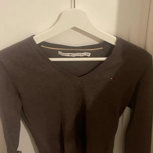 Brun tröja från Tommy Hilfiger - Säljer en snygg brun tröja från Tommy Hilfiger. Den är i storlek S och har en v-ringad hals. Tröjan är långärmad och perfekt för höst och vinter. Den är i bra skick och supermjuk!