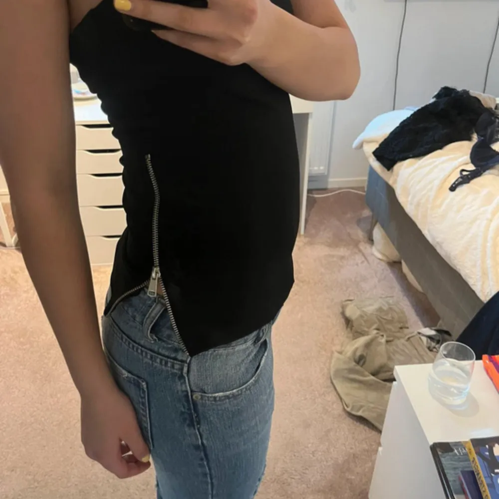 Säljer en snygg svart tubtopp som är perfekt för fest eller en utekväll. Toppen är axelbandslös och har en dragkedja på sidan för en cool detalj. Den är tight och sitter bra på kroppen. Passar perfekt till ett par jeans eller kjol! Lånade bilder fåen tidigare ägare. Säljer då den var lite stor på mig☺️❤️🩷. Yläosat.