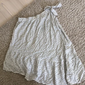 Vit prickig klänning från Kappahl - Säljer en superfin vit kjol. Den är perfekt för sommaren och passar både till vardags och fest. Materialet är lätt och luftigt, vilket gör den bekväm att bära hela dagen. Klänningen är i nyskick och har en lös passform.