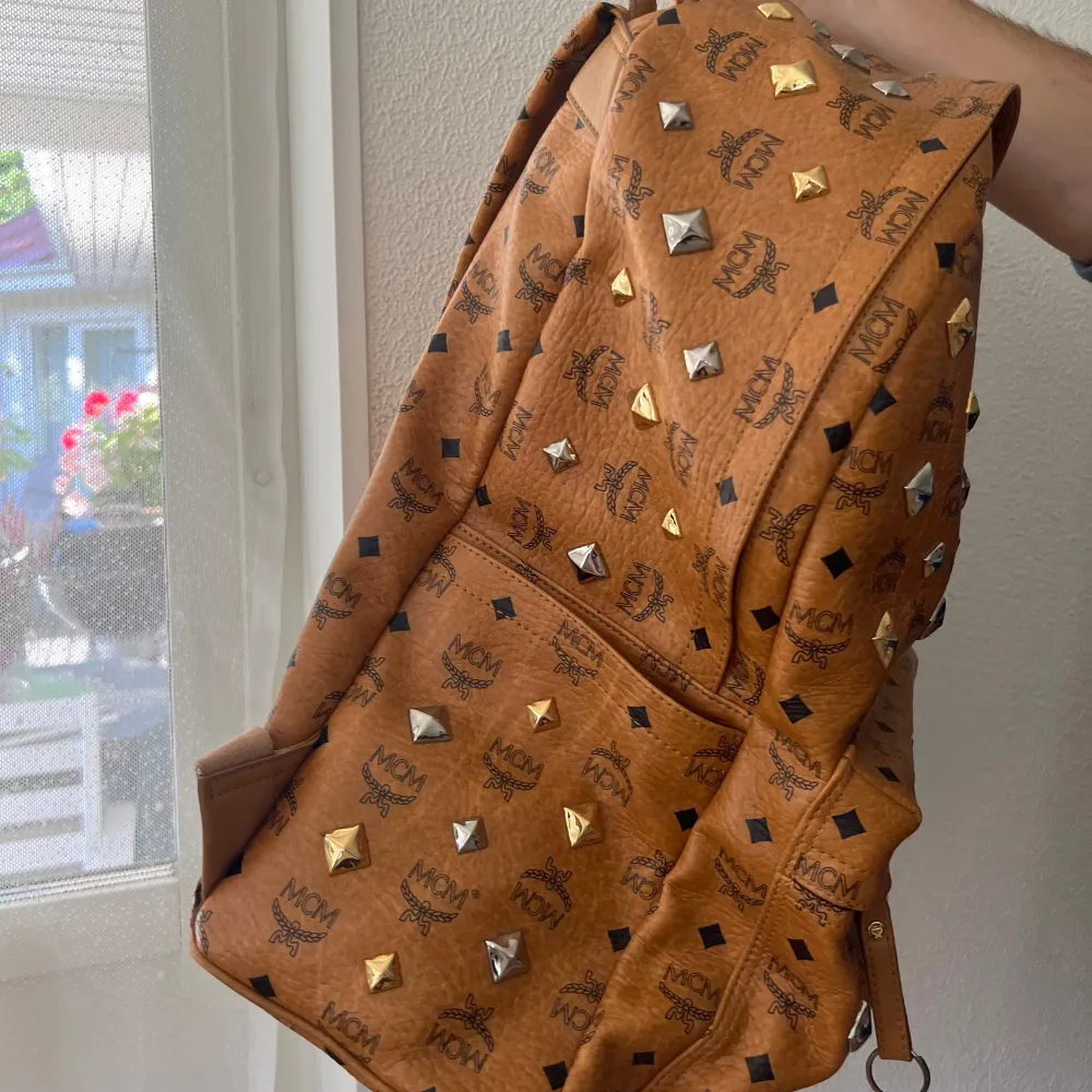 Säljer en eftertracktad vintage MCM (MCM backpack stark 30cm large)  som är väldigt svår att få tag på .Väskan är dekorerad med guld- och silverfärgade nitar och har MCM-loggan tryckt över hela ytan! sparsamt använd och ser helt ny ut, påsen är lite smutsig (kan ta bilder om ni frågar) . Väskor.