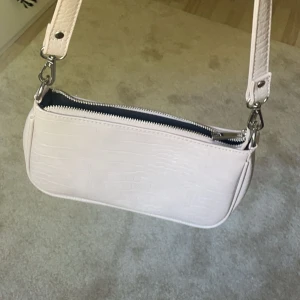 Beige axelväska från Gina Tricot - Säljer en snygg beige axelväska från Gina Tricot. Väskan är i nyskick och har en avtagbar axelrem.