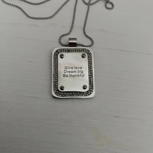 Snygg silvrig tag - Snyggt långt halsband med tag med kristaller runtomkring. Halsbandet är nytt från Bud to Rose och 90 cm långt.