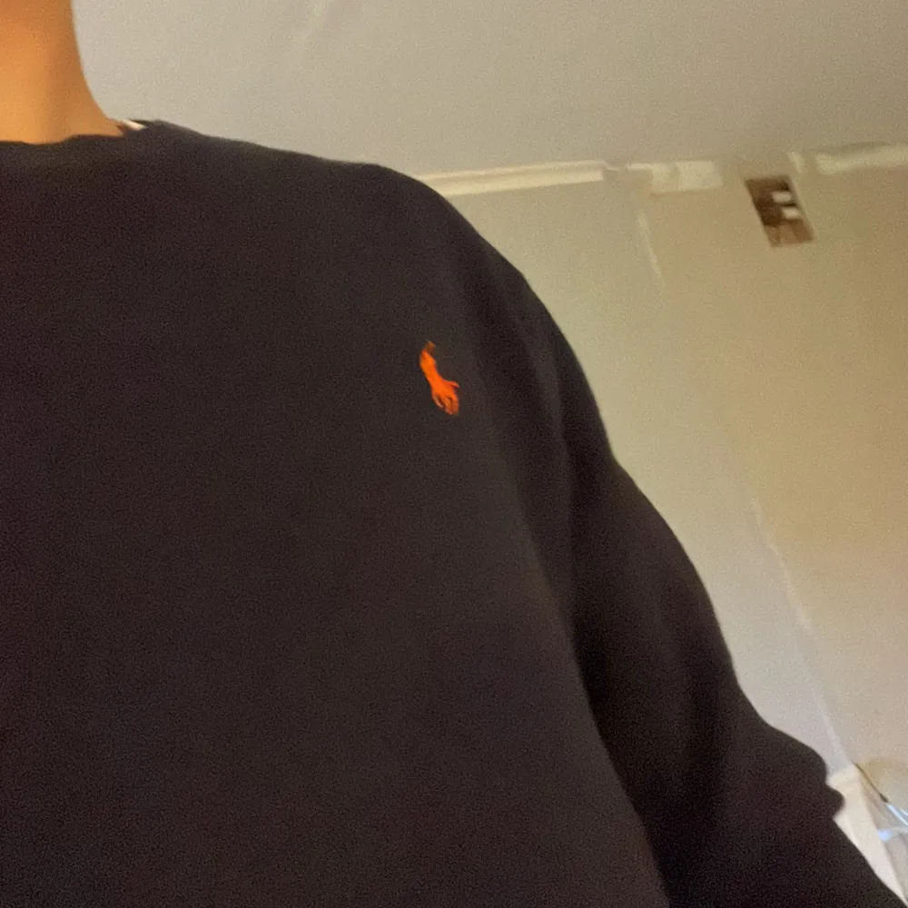 Säljer en snygg mörkblå tröja från Ralph Lauren. Den är i storlek M och har en liten orange logga på bröstet. Tröjan är långärmad och gjord av bomull, vilket gör den både bekväm och stilren. Perfekt för höst och sena sommarkvällar!!!. Tröjor & Koftor.