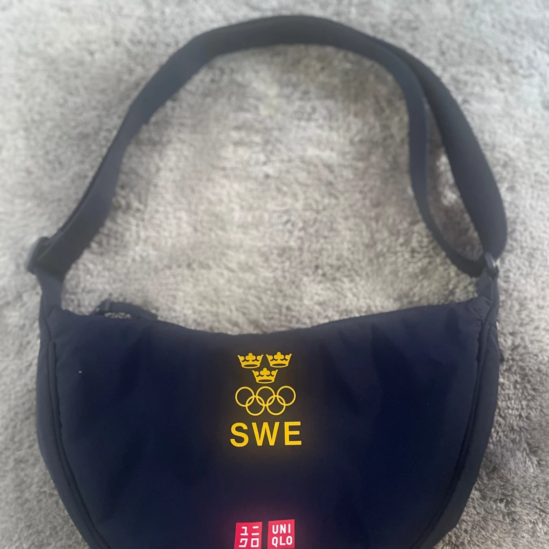 Blå axelväska från Uniqlo med SWE-tryck