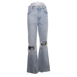 Ljusa jeans med hål på knäna - Säljer ett par snygga ljusa jeans med hög midja och hål på knäna. De har en bootcut-stil och är tillverkade i jeansmaterial. Perfekta för en avslappnad och trendig look! Mycket bra skick!
