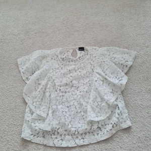 Vit spetsblus från Gina Tricot - Säljer en superfin vit spetsblus från Gina Tricot i storlek 38 (M). Blusen har korta ärmar och ett vackert blommigt spetsmönster. Perfekt för sommarens alla fester eller en dag på stan. Den är i nyskick och väldigt bekväm att ha på sig. Köp den nu och ge din garderob en romantisk touch! 💕