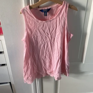 Rosa ärmlös topp från Polo Ralph Lauren - Säljer en söt rosa ärmlös topp från Polo Ralph Lauren. Den är i storlek L (12-14) och har fina spetsdetaljer längst ner. Perfekt för sommaren!💖 priset kan diskuteras 💕