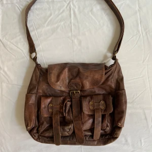 Brun axelremsväska  - Stor axelremsväska. Köpt secondhand. Bra skick utom några sömmar som är lite slitna. 