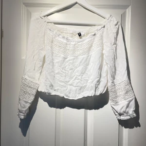 Vit blus från H&M Divided - Säljer en söt vit blus från H&M Divided med spetsdetaljer på ärmar och över bröstet. Blusen har långa ärmar och en offshoulder-design 