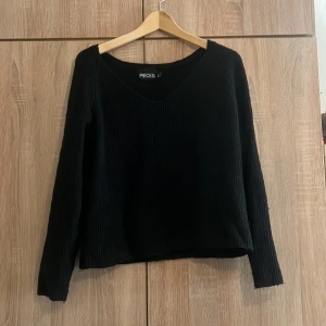 Svart ribbad tröja från Pieces - Säljer en stilren svart ribbad tröja från Pieces i markerad storlek M men passar även L. Tröjan har en v-ringad hals och långa ärmar, perfekt för både vardag och fest. Den är i mycket bra skick och passar till alla säsonger. 