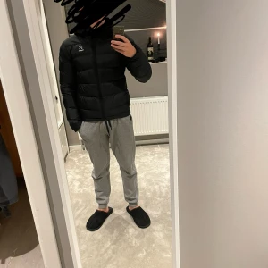 Svart pufferjacka från Haglöfs (Bield Down Hood jacket) - Säljer en svart pufferjacka från Haglöfs. Jackan har en stilren design med dragkedja och är perfekt för kyligare väder. Den är långärmad och quiltad för extra värme. Passar bra för både höst och vinter. Inga skador eller defekter. Nypris  2000kr+