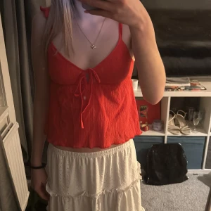 Röd ribbad topp från Nelly - Säljer en söt röd ribbad topp från Nelly med knytning framtill. Toppen har smala axelband och en lätt croppad passform. Använd cirka 2 gånger, skriv för mer information💕