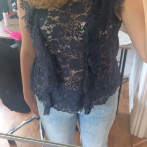 Svart spetslinne - Säljer en elegant svart spetslinne med vackra blommönster. Toppen är ärmlös också. Den är ganska använd men inte nu på sistone då den är för liten. Inte stretchig