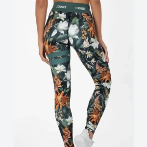 Blommiga träningsbyxor från Stronger - Snygga träningsbyxor med blommigt mönster i grönt, vitt och orange från Stronger. Perfekta för träning med hög midja och elastiskt material för bästa komfort. De har också dekorativa banddetaljer på låren. Inga defekter!