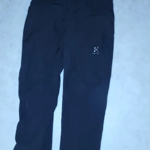 Svarta byxor från Haglöfs - Säljer ett par svarta byxor från Haglöfs. Perfekta för utomhusaktiviteter med en bekväm passform. Byxorna har en diskret logga på benet och är tillverkade i ett slitstarkt material.