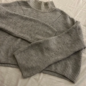 Grå stickad tröja från Gina Tricot - Mysig grå stickad tröja från Gina Tricot i storlek S. Perfekt för kyliga dagar med sin ribbade design och långa ärmar. Tröjan har en hög krage och ett diskret mönster som ger den en stilren look. Passar både till vardags och mysiga hemmakvällar. Nästan aldrig använd💕