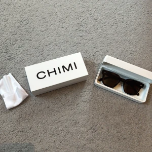 Svarta solglasögon från CHIMI - Säljer ett par snygga bruna solglasögon från CHIMI i nyskick. De har en klassisk fyrkantig form och kommer med originalförpackning och putsduk. Perfekta för både vardag och fest! Modellen är 04 och köptes på NK för 2000 kr.