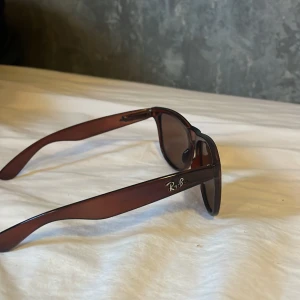 Bruna solglasögon från Ray-Ban - Snygga bruna solglasögon från Ray-Ban i mycket bra skick. De har en klassisk design med bruna bågar och mörka linser, perfekt för både vår och sommar. Passar lika bra till stranden som till en utekväll. Ett måste för den stilmedvetna!