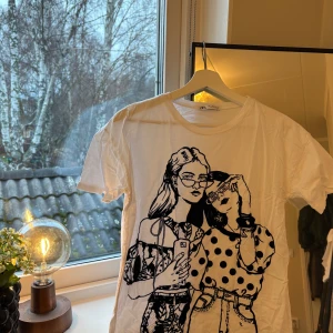 Vit t-shirt med tryck från Zara - Säljer en vit t-shirt från Zara med ett coolt tryck av två tjejer . T-shirten är kortärmad och i bomull, perfekt skick. 🖤