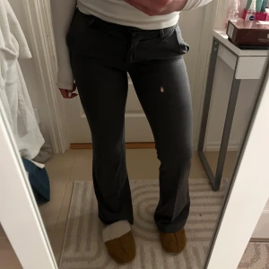 Grå kostymbyxor - Säljer ett par snygga grå kostymbyxor i mycket bra skick. De är lågmidjade och har en klassisk straight passform som passar perfekt för både jobb och fest. Byxorna är gjorda i ett bekvämt material som ger en stilren look. Perfekta för höst och vinter!