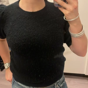 Svart stickad tröja från Vero Moda - Säljer en svart stickad tröja från Vero Moda i storlek XS. Tröjan har korta ärmar och en bekväm passform. Den är i bra skick och supermjuk att ha på sig. Passar perfekt till jeans eller kjol!