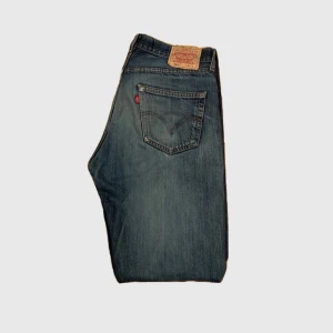 Levis jeans med slitningar - Säljer ett par klassiska Levis 501 jeans i blå denim med slitningar på framsidan. De har en straight passform och är midwaist. Perfekta för en avslappnad stil. Med unik tvätt och efter andvändning har de skapat sin egen karaktär. W34 L32. Bara att höra av er vid frågor och funderingar. 
