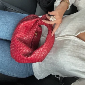 Röd flätad handväska - Snygg röd handväska med flätat mönster och en kort rem. Perfekt för att ge en färgklick till din outfit. Väskan har en stilren design och är lätt att bära med sig. Väskan är endast använd 1 gång🥰
