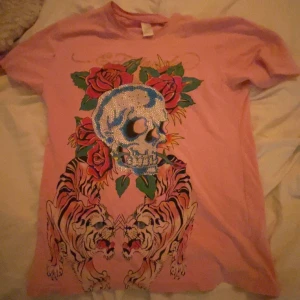 Ljusrosa Ed-Hardy t-shirt - Säljer än otroligt snygg och cool ed Hardy tröja! Majoriteten av alla rhinestones är kvar och den har ett sjukt coolt tryck både där bak och där fram på tröjan! Materialet är sjukt najs och passformen är perfekt 💓
