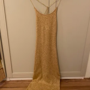Guldglittrig långklänning - Säljer stickad långklänning med smala axelband i guld. Perfekt för nyårsfesten!!🥂🥂🐆❤️‍🔥