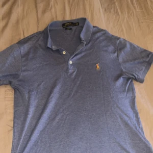 Blå piké från Ralph Lauren - Säljer en snygg blå piké från Ralph Lauren med passform slim fit. Materialet är mjuk och lite stretchigt vilket gör den väldigt komfortabel.