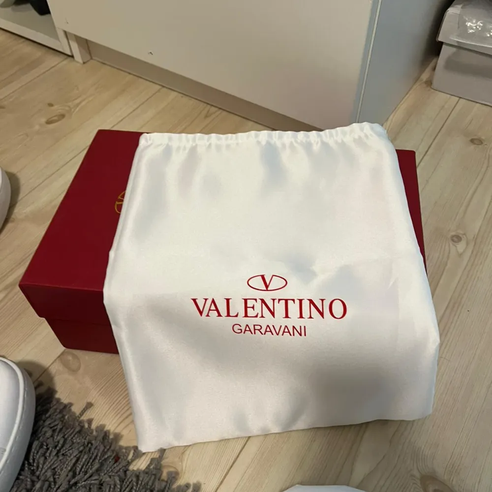 Säljer ett par snygga Valentino Garavani sneakers i vitt med en grön detalj. Skorna är i nytt skick och kommer med originalförpackning och dustbag. Perfekta för både vardag och fest! 🏷️. Skor.