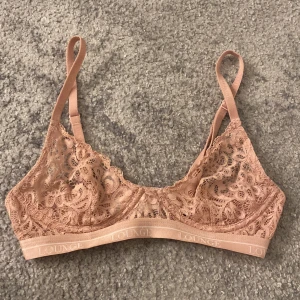 Ljusrosa spets-bh från Lounge  - Säljer en superfin rosa/beige spets-bh från Lounge Underwear. Den har justerbara axelband och en bekväm passform. Perfekt för både vardag och speciella tillfällen. Materialet är 90% polyamid och 10% spandex, vilket gör den både mjuk och stretchig.