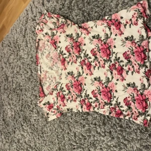 Blommig klänning från Amisu - Söt blommig klänning från Amisu i storlek XS. Den har ett vackert mönster med rosa och röda blommor på en vit bakgrund. Klänningen är kortärmad och perfekt för sommarens varma dagar.