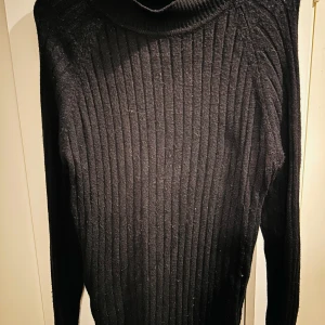 Svart ribbad polotröja från JDY - Säljer en stilren svart ribbad polotröja från JDY. Perfekt för kyliga dagar med sin mjuka och bekväma passform. Tröjan har långa ärmar och en klassisk polokrage som håller dig varm och snygg. Passar både till vardags och lite finare tillfällen. 🖤