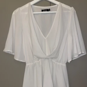 Vit blus från Boohoo - Säljer en elegant vit blus . Den har en v-ringad design och kortärmade ärmar som ger en luftig känsla!