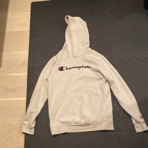 Beige hoodie från Champion - Säljer en beige hoodie från Champion i storlek X-Large. Den är gjord av en mjuk bomulls- och polyesterblandning, perfekt för kyliga dagar. Hoodien har en klassisk Champion-logga på bröstet och en praktisk magficka. Perfekt för både vardag och träning!