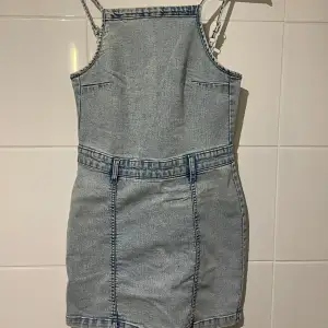 Säljer en snygg jeansklänning i ljusblå denim med smala axelband. Klänningen har en tight passform och är perfekt för sommardagar. Den är ifrån H&M och passar de som har str XS/S