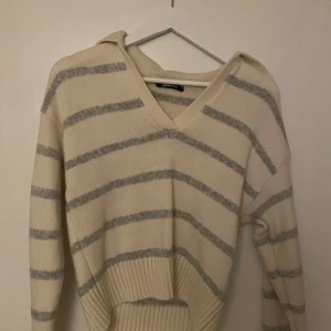 Randig tröja från Gina Tricot - Säljer en superfin randig tröja från Gina Tricot i storlek XS. Den är vit med grå ränder och har en v-ringad hals. Perfekt för både höst och vår! Tröjan är stickad och har långa ärmar, vilket gör den både mysig och stilren. Passar perfekt till jeans eller kjol!