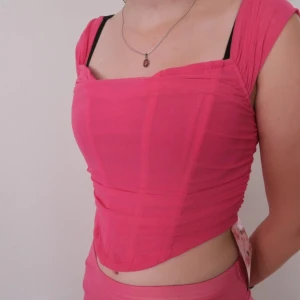 Rosa topp från Shein - Säljer en snygg rosa topp från Shein. Den är croppad och har en dragkedja bak. Perfekt för sommaren eller en festkväll! Toppen har en tight passform och är axelbandslös med breda axelband.