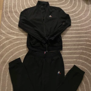 Svarta mjukisbyxor från Le Coq Sportif - Säljer ett par svarta mjukisbyxor från Le Coq Sportif. De är i nyskick och har en liten broderad logga på sidan. Perfekta för en avslappnad dag eller träning. Byxorna har en elastisk midja för extra komfort.