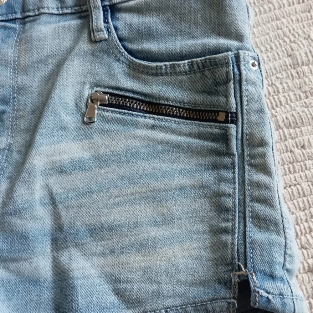 Säljer ett par ljusblå jeansshorts från &Denim. De har en snygg slitning och två dragkedjor framtill för extra stil. Perfekta för sommardagar!. Shorts.