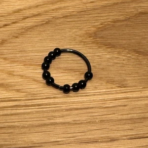 Svart pärlring - Säljer en stilren svart ring med små pärlor. Perfekt för att ge en elegant touch till din outfit. Ringen är enkel men ändå iögonfallande, och passar både till vardags och fest. Ett måste för smyckesälskare! 🖤
