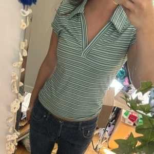 Randig topp från Yook - Säljer en superfin randig topp från Poof . Den har en v-ringad design och är i en härlig mix av blå, grön och vit! Toppen är i ett mjukt och skönt material, perfekt för vardagsbruk. Kommer inte till användning därför säljer jag🥰