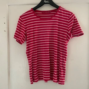 Röd- och vitrandig t-shirt från OLÉS - Säljer en superfin röd- och vitrandig t-shirt från OLÉS. Den är kortärmad och perfekt för sommardagar. T-shirten är i bra skick och har en klassisk rund halsringning. Perfekt för en avslappnad stil!