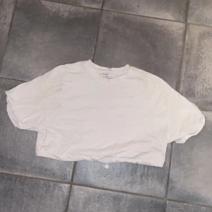 Croppad tshirt med dragsko - Vit croppad tisha med dragsko så du kan få den att sitta tightare/lösare beroende på vad du känner för i stunden! 