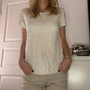 Glittrig vit t-shirt - Säljer en superfin glittrig vit t-shirt som är perfekt för både vardag och fest. Den har en normal passform och korta ärmar. Materialet är mjukt och bekvämt💕
